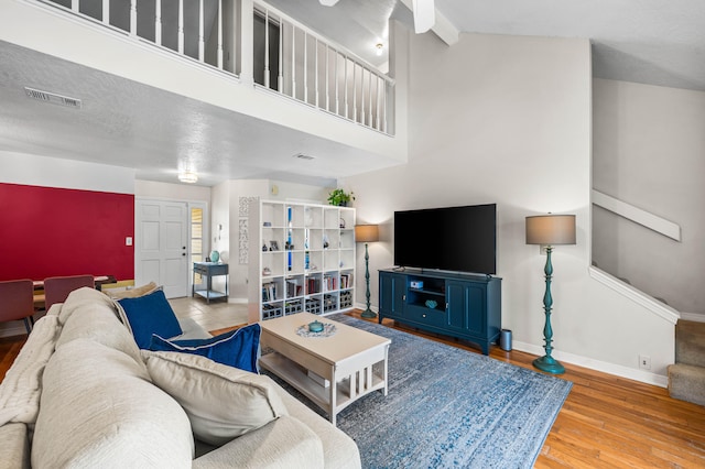 living room featuring light wood-type flooring, high vaulted ceiling, and beamed ceiling