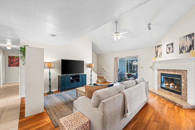 living room with light wood-type flooring, vaulted ceiling, and a textured ceiling