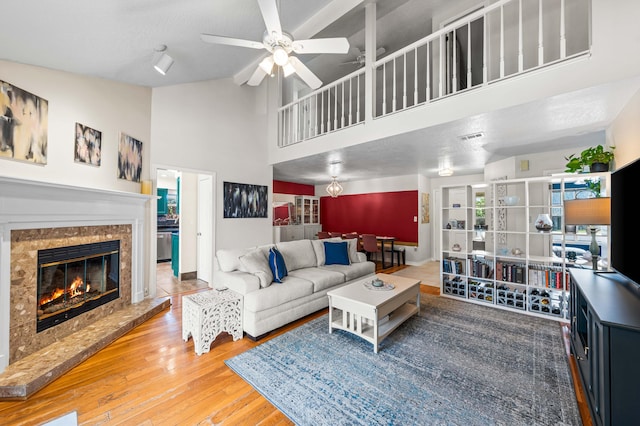 living room featuring a fireplace, high vaulted ceiling, ceiling fan, and wood-type flooring