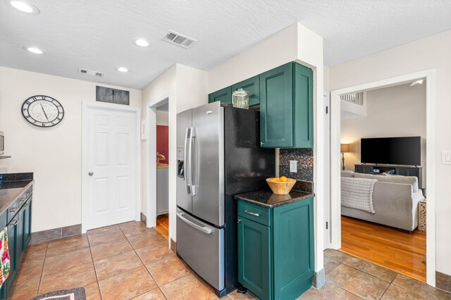 kitchen with stainless steel fridge with ice dispenser, green cabinets, tasteful backsplash, a textured ceiling, and light tile patterned floors