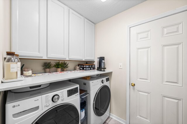 laundry room featuring washing machine and clothes dryer, a textured ceiling, and cabinets