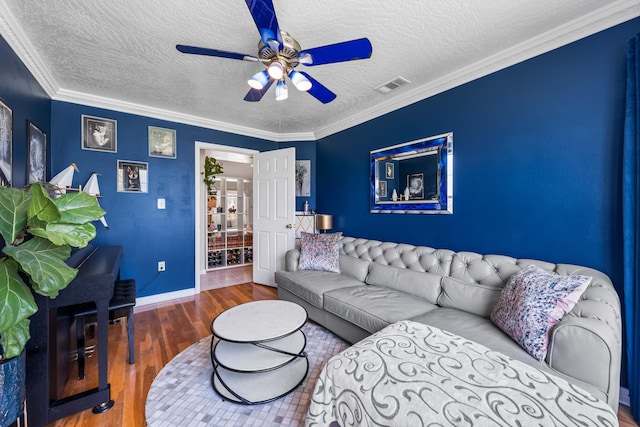 living room with a textured ceiling, ceiling fan, hardwood / wood-style floors, and crown molding