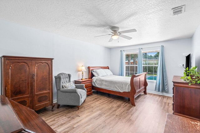 bedroom featuring a textured ceiling, light hardwood / wood-style flooring, and ceiling fan