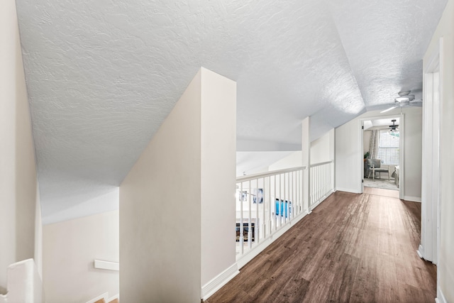 corridor featuring a textured ceiling, lofted ceiling, and wood-type flooring