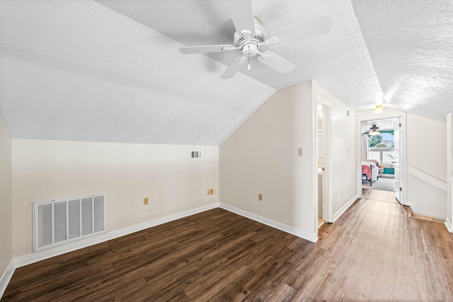 additional living space featuring a textured ceiling, ceiling fan, vaulted ceiling, and wood-type flooring