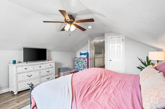 bedroom featuring ceiling fan, vaulted ceiling, a textured ceiling, and wood-type flooring