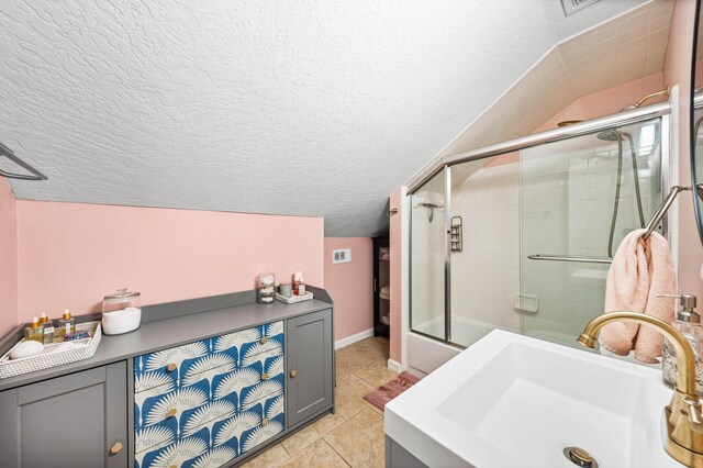 bathroom with sink, a textured ceiling, tile patterned floors, and lofted ceiling