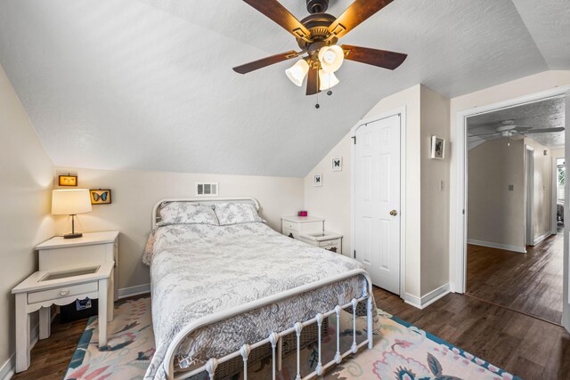 bedroom with dark hardwood / wood-style floors, a textured ceiling, lofted ceiling, a closet, and ceiling fan