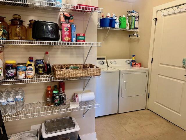 laundry area with washing machine and clothes dryer and light tile patterned floors