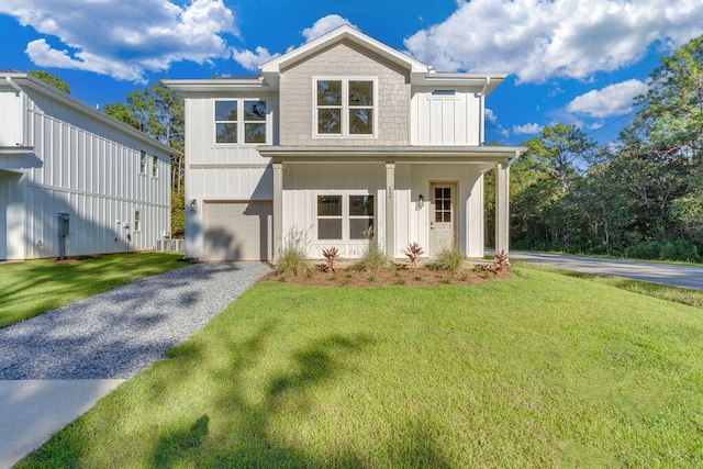 view of front of property featuring board and batten siding, a front yard, and driveway