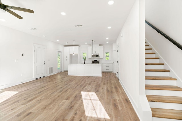 unfurnished living room with light wood-type flooring, visible vents, and a healthy amount of sunlight