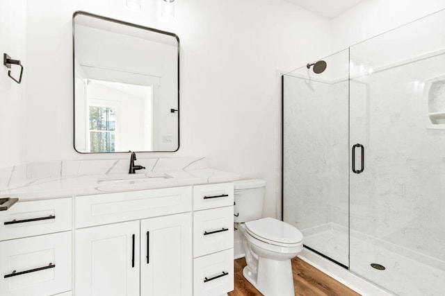 bathroom featuring toilet, wood finished floors, vanity, and a shower stall