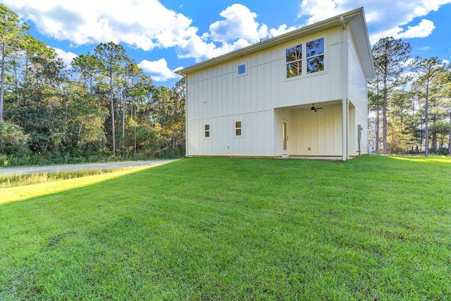 rear view of house with a ceiling fan, a yard, and board and batten siding