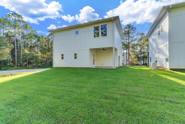 rear view of property featuring central AC, a ceiling fan, board and batten siding, and a yard