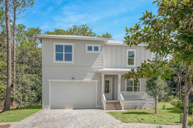 view of front of property with metal roof, an attached garage, decorative driveway, board and batten siding, and a standing seam roof