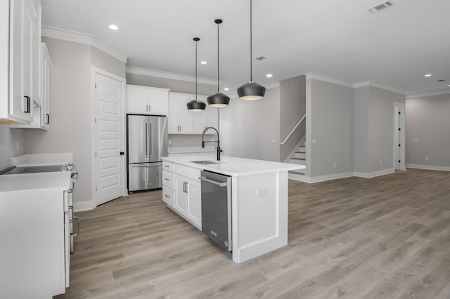 kitchen featuring appliances with stainless steel finishes, a kitchen island with sink, light countertops, white cabinetry, and a sink