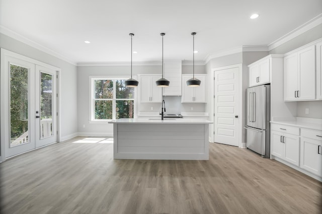 kitchen with decorative light fixtures, light countertops, white cabinetry, an island with sink, and high end refrigerator