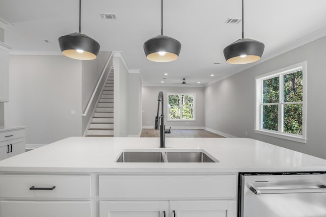 kitchen featuring pendant lighting, light countertops, visible vents, white cabinets, and a sink