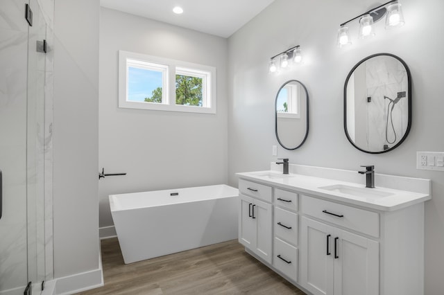 bathroom featuring wood finished floors, a soaking tub, a sink, and a marble finish shower