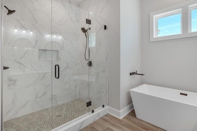 full bath with a soaking tub, a marble finish shower, baseboards, and wood finished floors