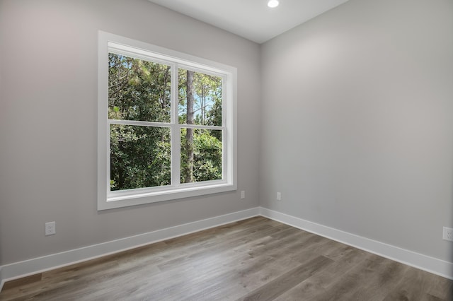 empty room featuring recessed lighting, baseboards, a wealth of natural light, and wood finished floors