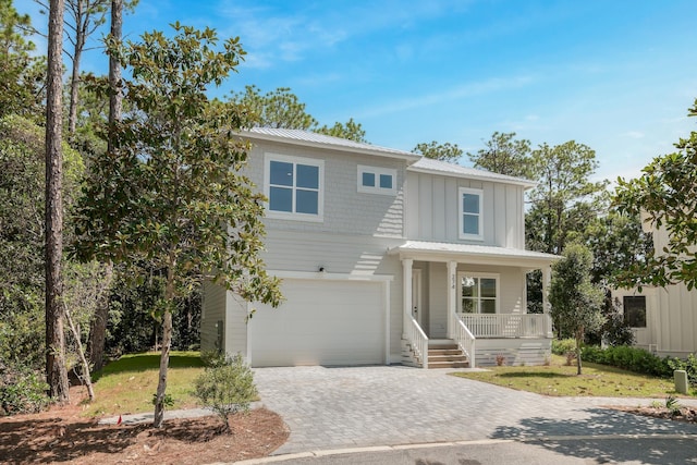 view of front facade featuring a garage, metal roof, covered porch, decorative driveway, and board and batten siding