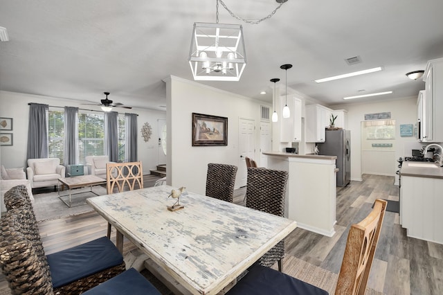 dining room with sink, crown molding, and wood-type flooring