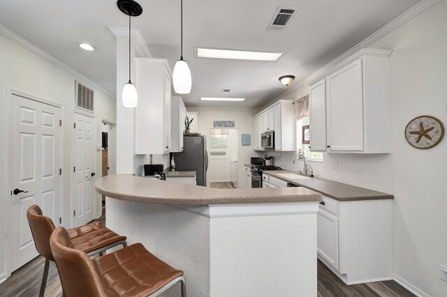 kitchen with white cabinetry, kitchen peninsula, stainless steel appliances, and decorative light fixtures