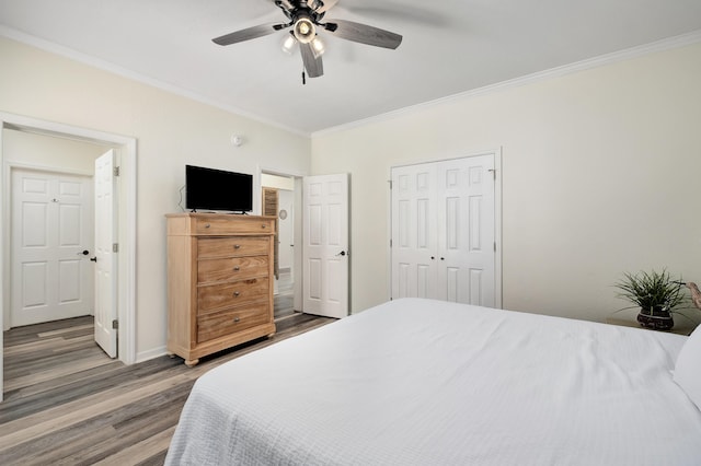 bedroom with ceiling fan, crown molding, wood-type flooring, and a closet