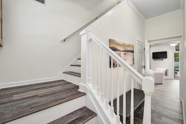 stairs featuring crown molding and wood-type flooring