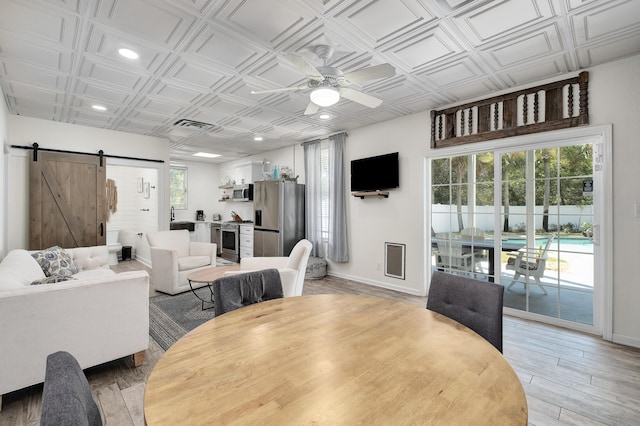 dining area featuring hardwood / wood-style flooring, ceiling fan, and a barn door