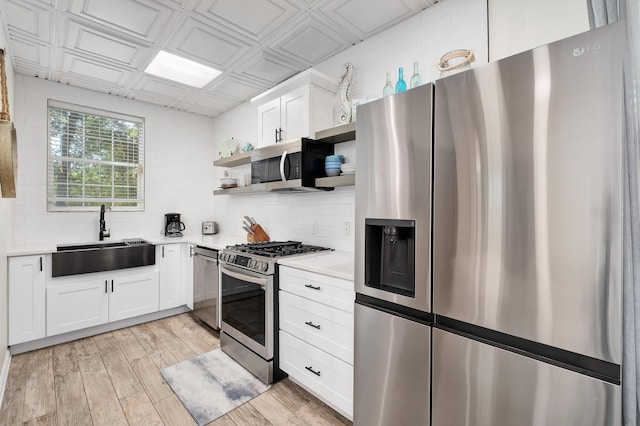 kitchen with appliances with stainless steel finishes, decorative backsplash, sink, and white cabinets