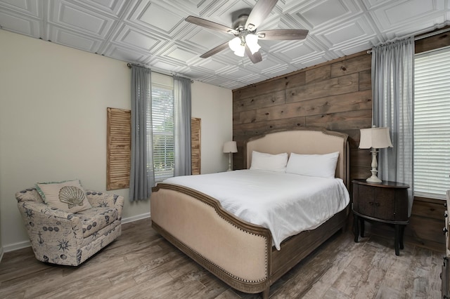 bedroom with hardwood / wood-style flooring, ceiling fan, and wood walls