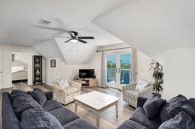 living room with light wood-type flooring, vaulted ceiling, ceiling fan, and french doors