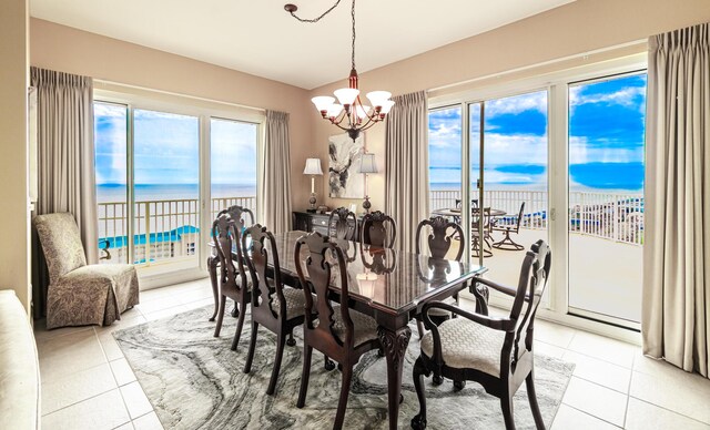 dining area with a beach view, a notable chandelier, a water view, and light tile patterned floors