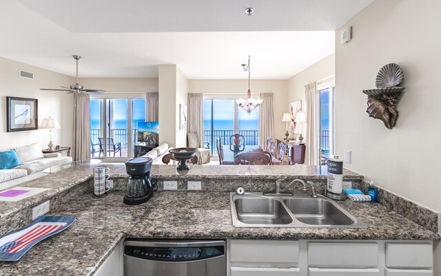 kitchen featuring dark stone counters, sink, ceiling fan with notable chandelier, dishwasher, and hanging light fixtures