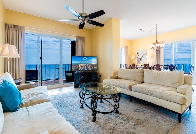 living room with a wealth of natural light, ceiling fan with notable chandelier, and light tile patterned flooring