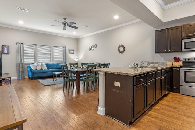 kitchen with visible vents, appliances with stainless steel finishes, open floor plan, a peninsula, and a sink