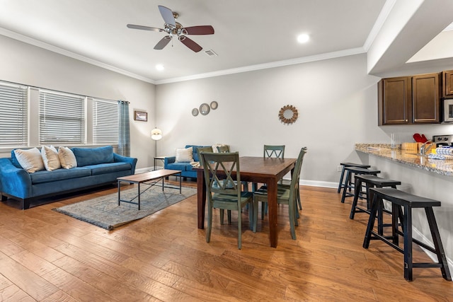 dining space with ornamental molding, visible vents, light wood-style flooring, and baseboards