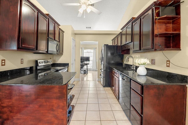 kitchen featuring sink, dark stone countertops, light tile patterned floors, and stainless steel appliances