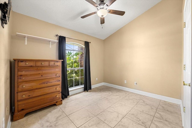 empty room featuring a textured ceiling, ceiling fan, light tile patterned floors, and vaulted ceiling