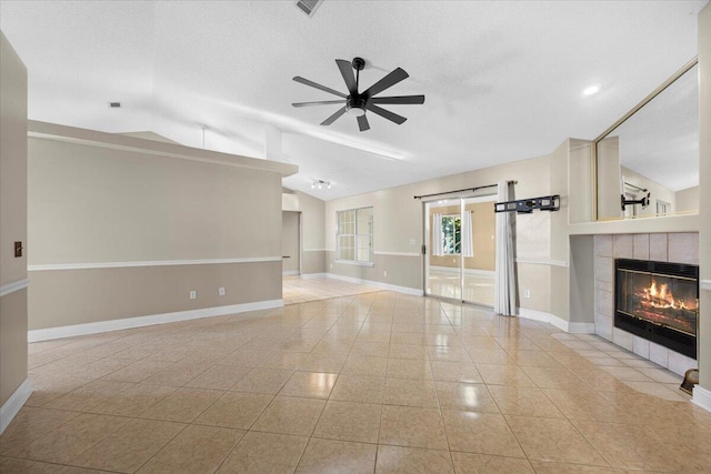 unfurnished living room with light tile patterned floors, ceiling fan, lofted ceiling, and a tiled fireplace