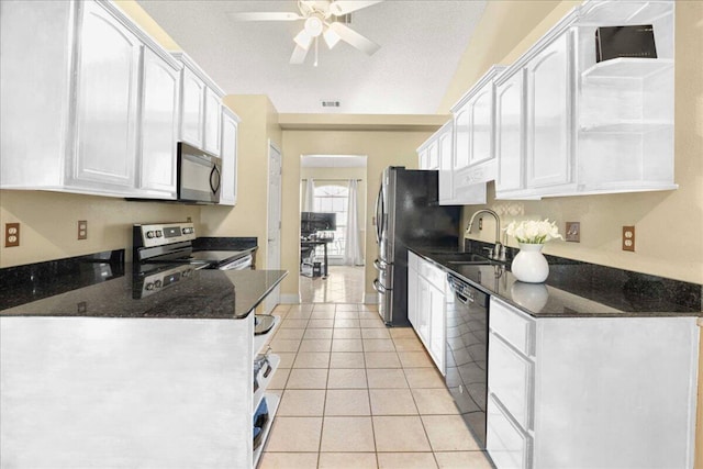 kitchen with dark stone counters, white cabinets, sink, appliances with stainless steel finishes, and light tile patterned flooring