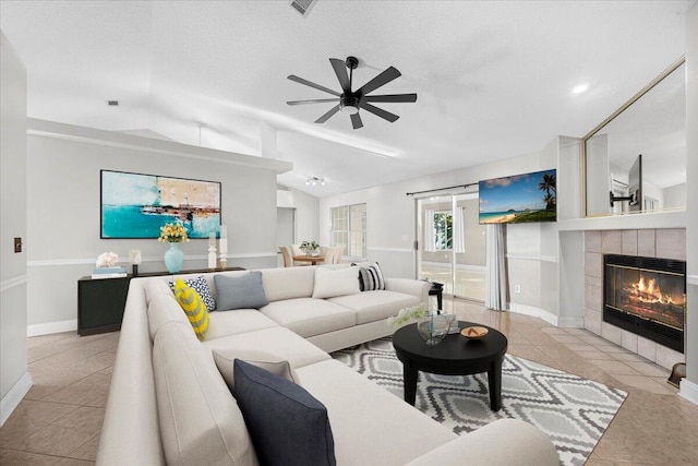 living room with a tile fireplace, ceiling fan, light tile patterned floors, and vaulted ceiling