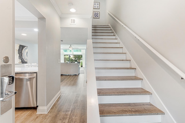 stairway with crown molding, hardwood / wood-style floors, and ceiling fan