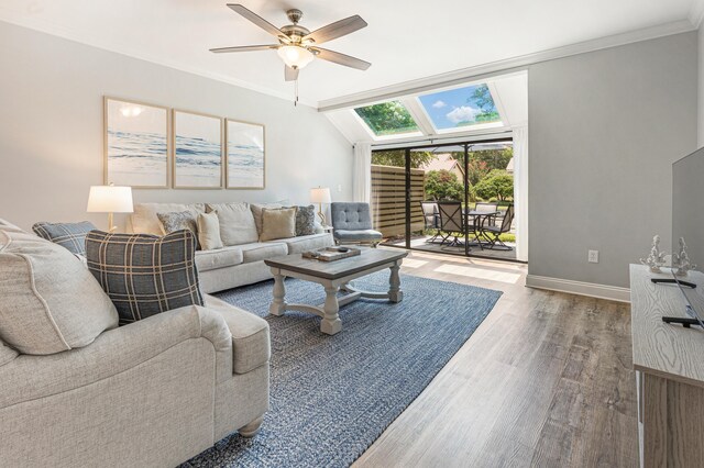 living room with ceiling fan, wood-type flooring, vaulted ceiling, and ornamental molding