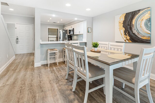 dining space featuring crown molding and light hardwood / wood-style flooring