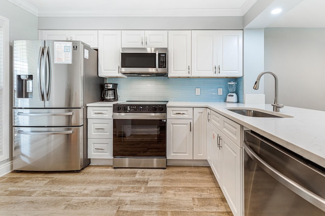 kitchen with light wood-type flooring, stainless steel appliances, white cabinetry, and sink