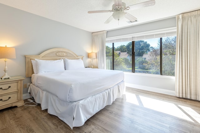 bedroom featuring ceiling fan, dark hardwood / wood-style floors, and a textured ceiling