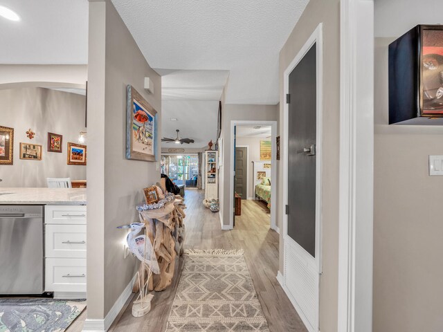 corridor with a textured ceiling and light hardwood / wood-style flooring